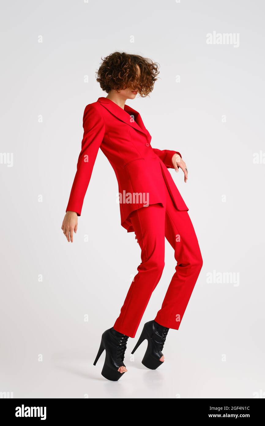 Graceful woman in red pantsui and pole dance boots arched and stands on tiptoe Stock Photo