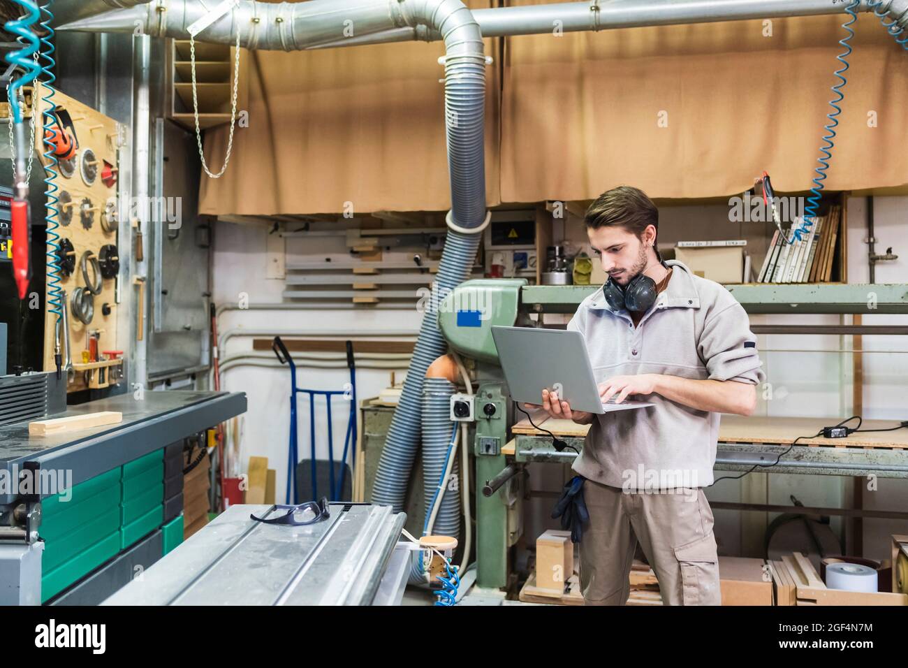 Male owner using laptop while standing at workshop Stock Photo