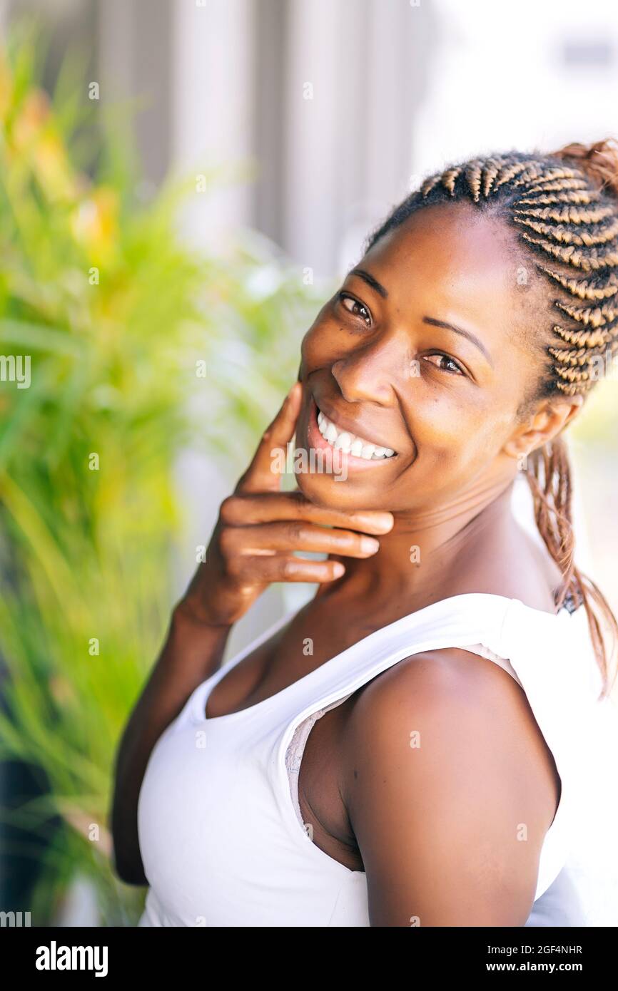 Woman with braided hair smiling while touching face Stock Photo