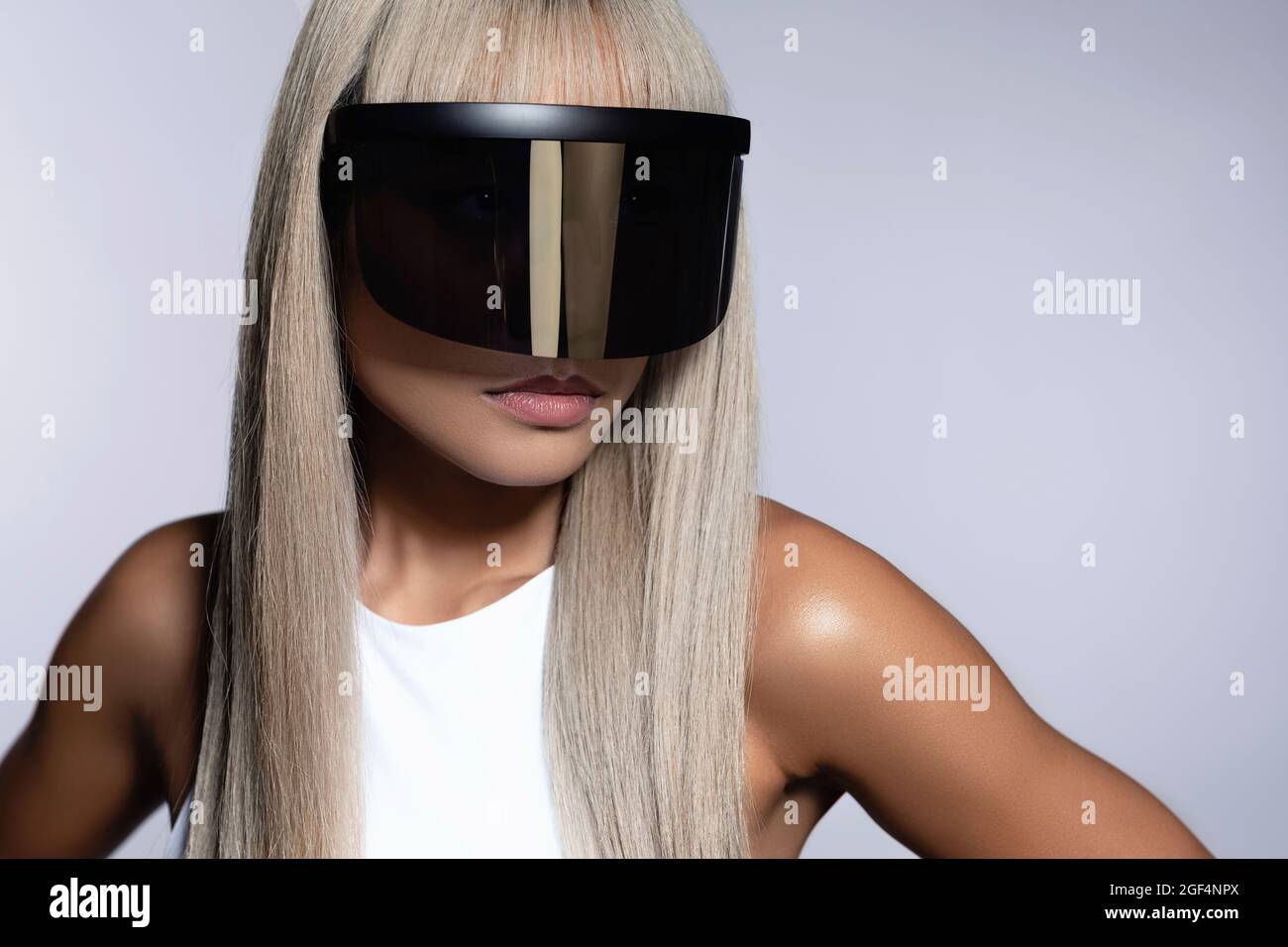 Woman with dyed hair wearing black visor glasses against white background Stock Photo