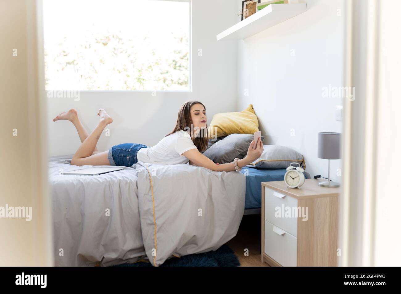 Woman taking selfie through smart phone while lying on bed at home Stock Photo