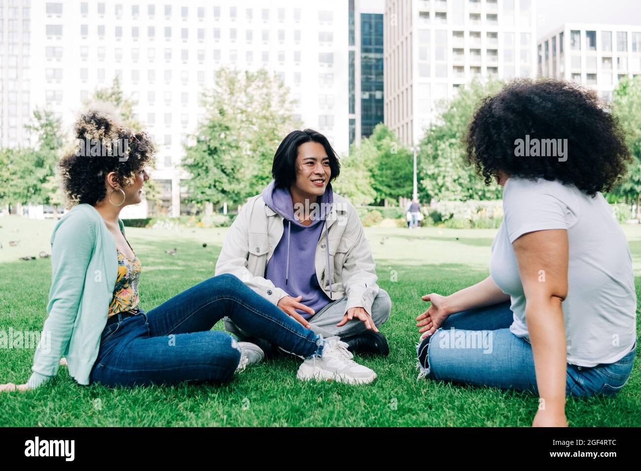 Young man talking to multi ethnic female friends at park Stock Photo