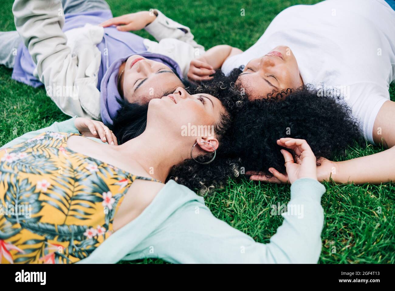 Young male and female friends lying on grass at park Stock Photo