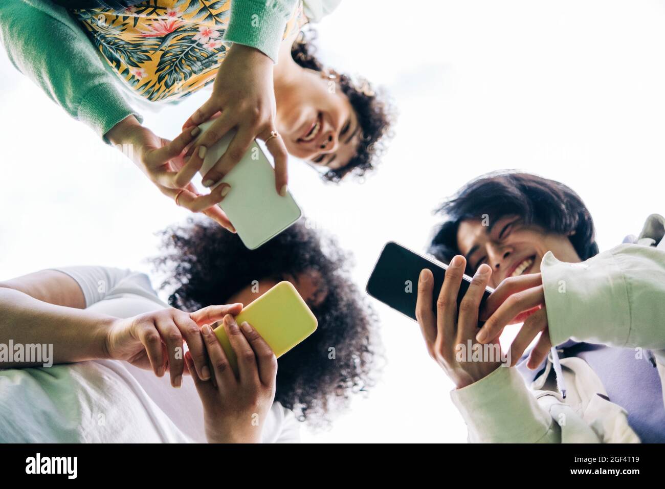 Multi-ethnic male and female friends using smart phones Stock Photo