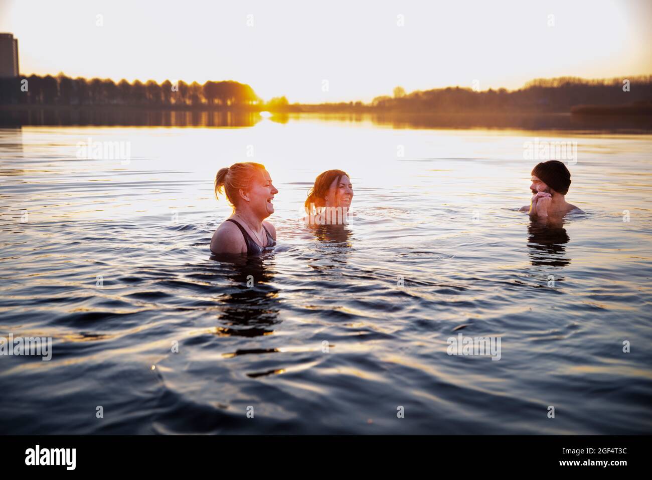 Cheerful women enjoying in water while looking at male friend Stock Photo