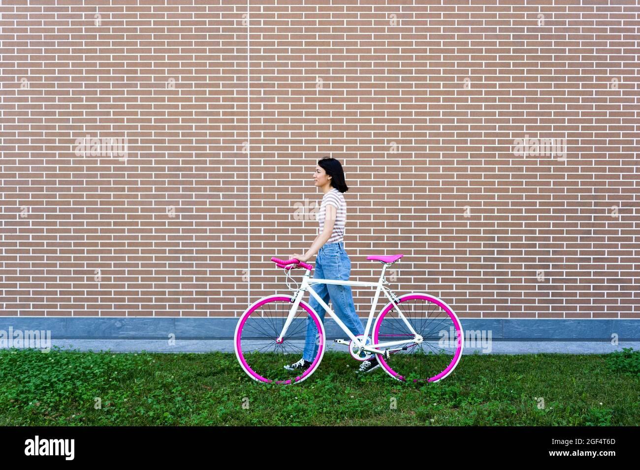 Young woman looking away while wheeling bicycle Stock Photo
