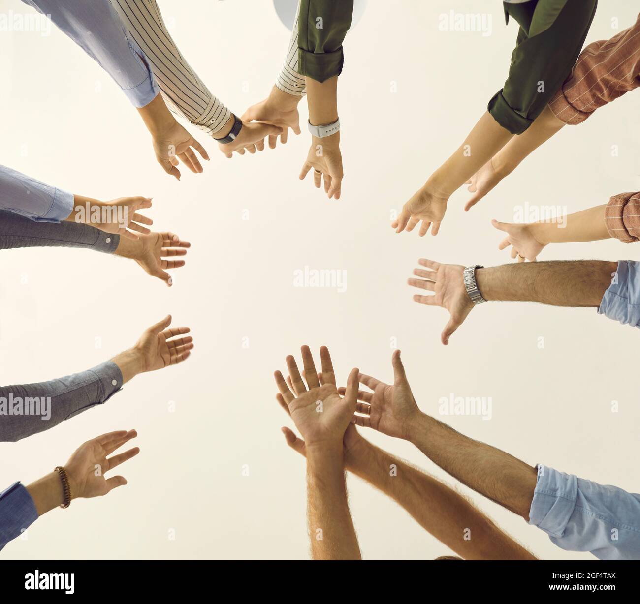 Shot from below of community or team of people reaching up together and joining hands Stock Photo