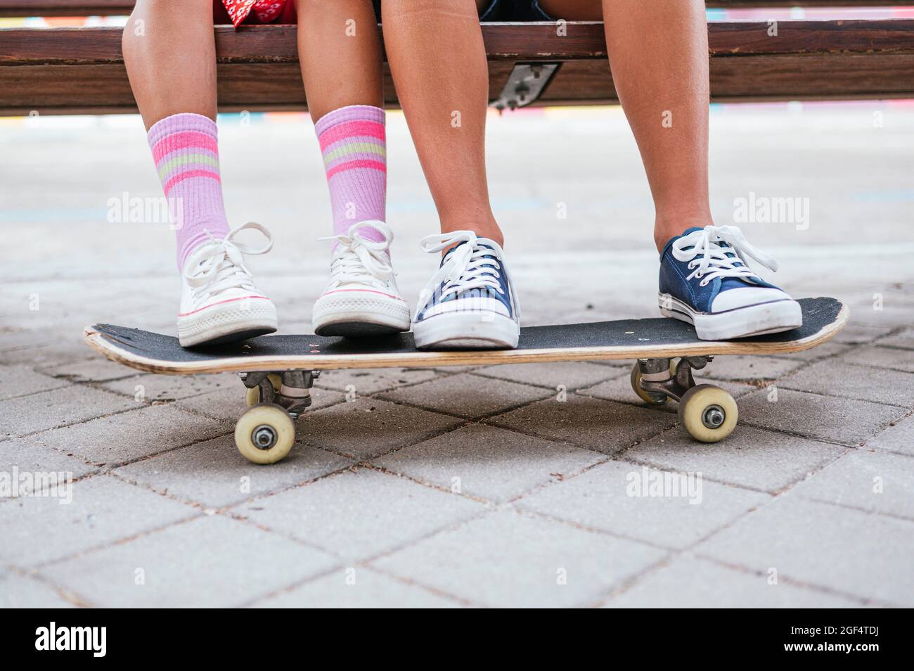 Friends using mobile phone while sitting on bench Stock Photo