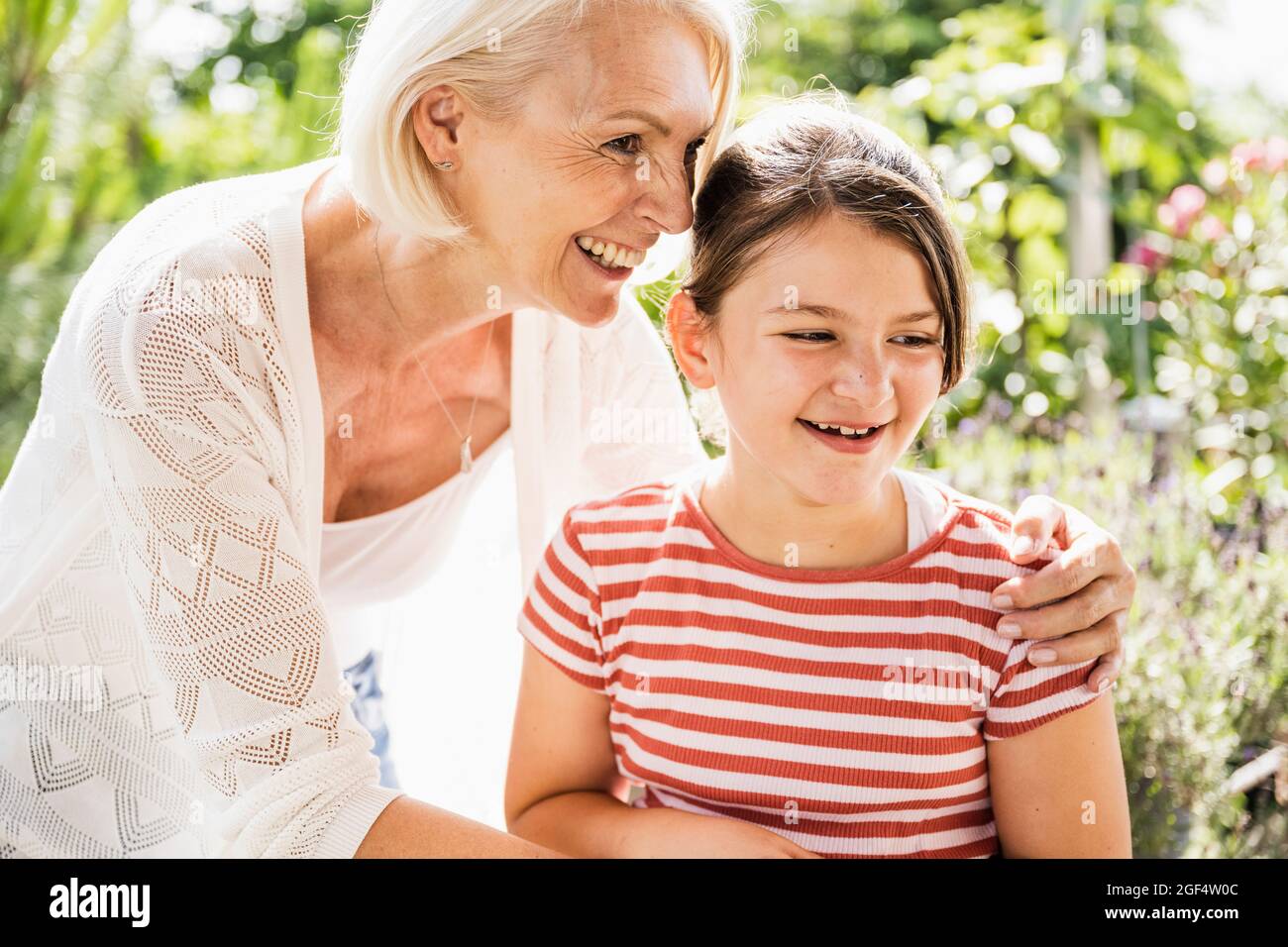Smiling grandmother standing with arm around granddaughter Stock Photo