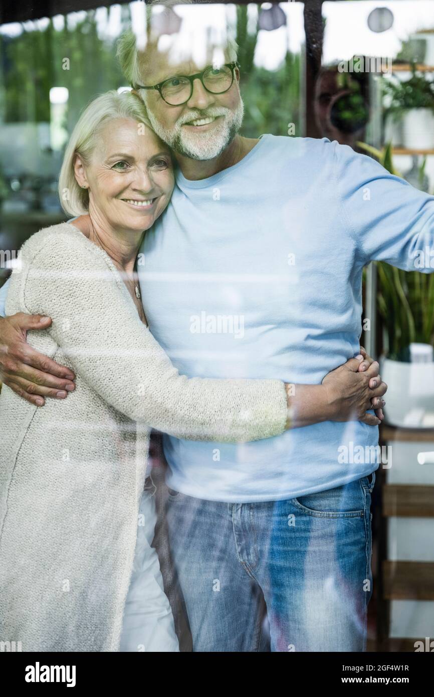 Smiling couple standing seen through glass window Stock Photo