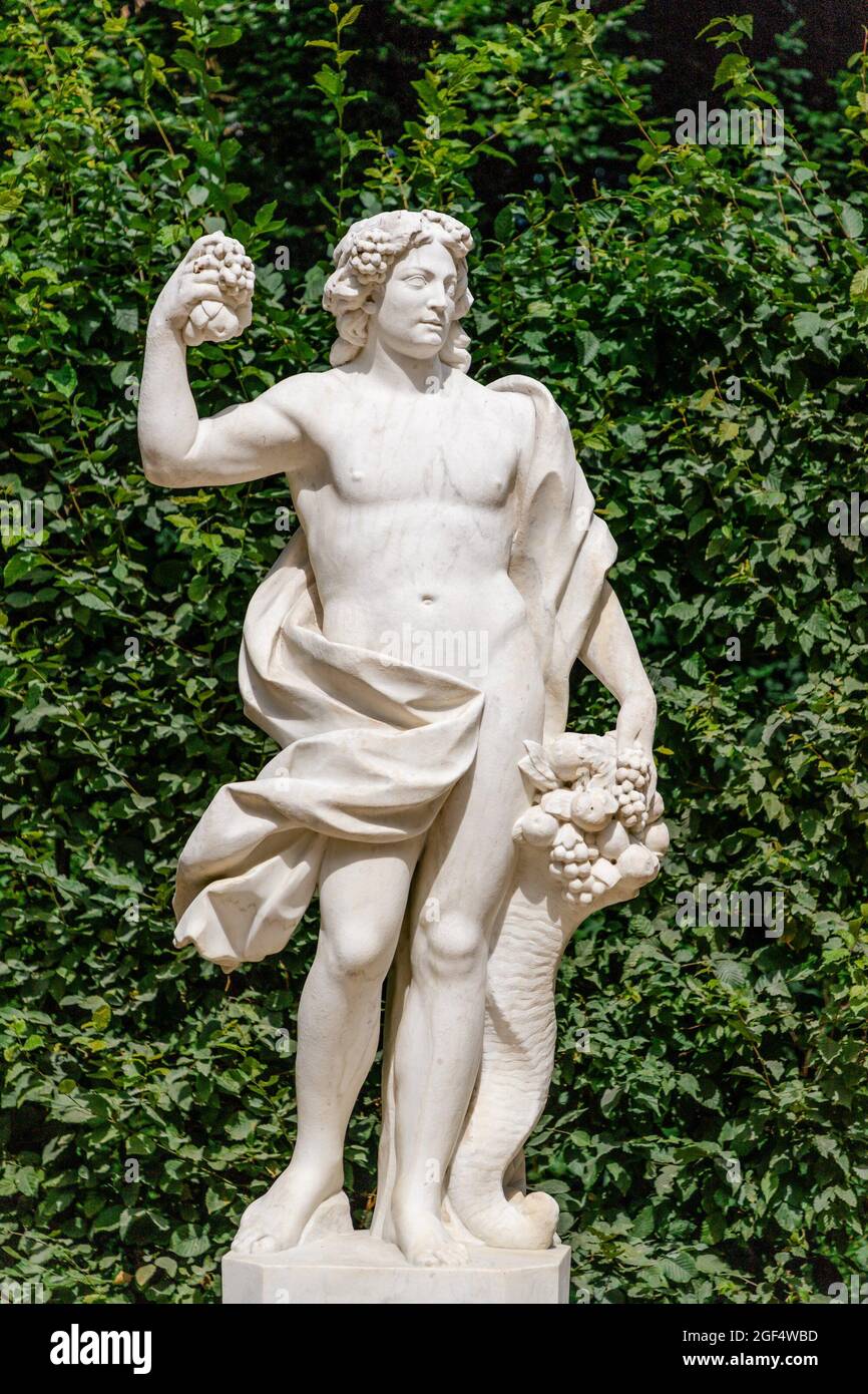 Statue with cornucopia on green leaves background at the Sanssouci palace. Potsdam, Germany Stock Photo