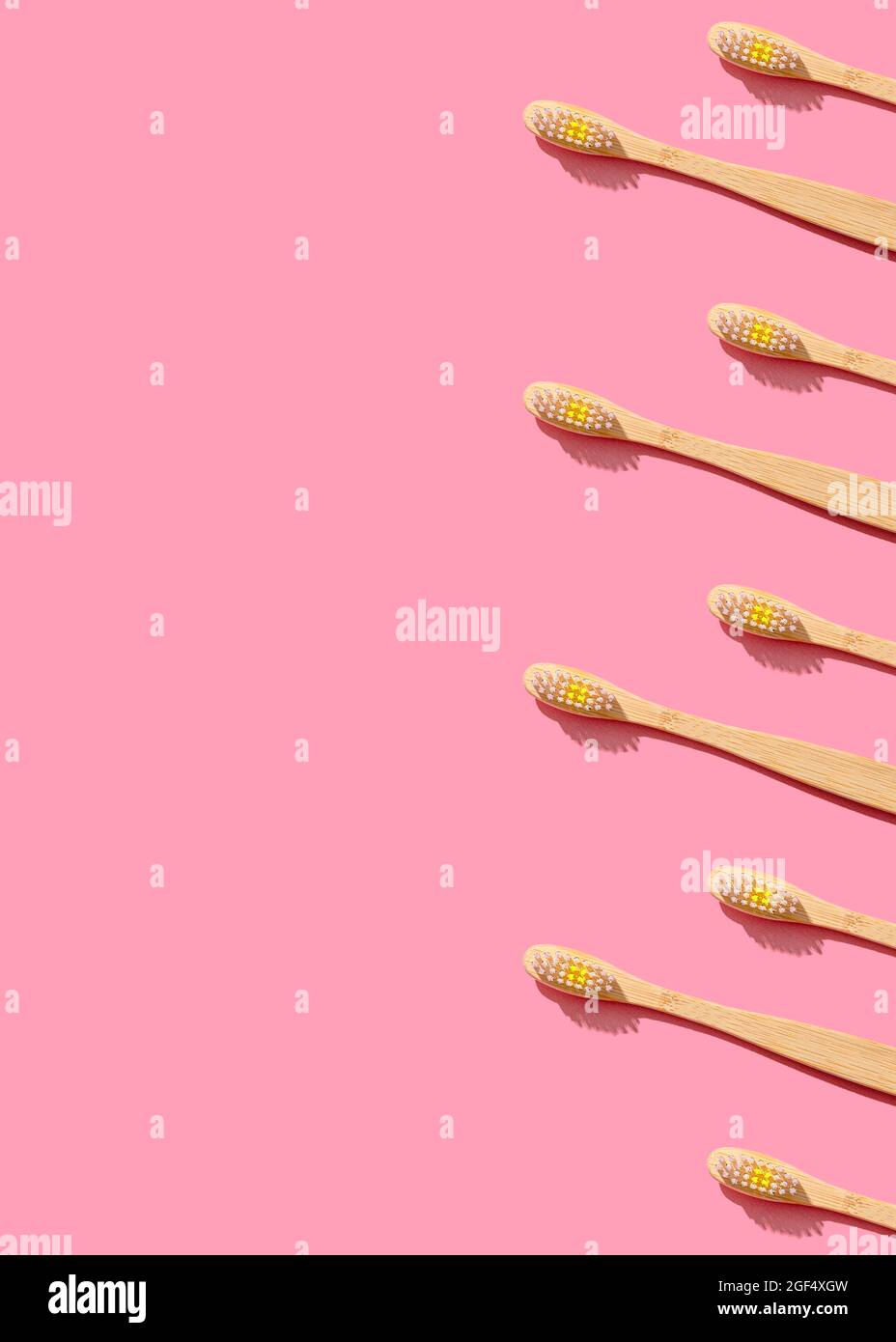 Pattern of wooden toothbrushes flat laid against pink background Stock Photo