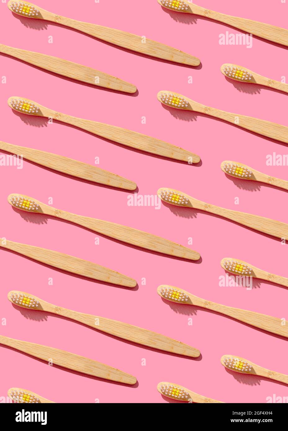 Pattern of wooden toothbrushes flat laid against pink background Stock Photo