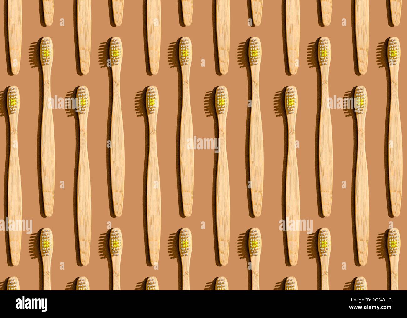 Pattern of wooden toothbrushes flat laid against brown background Stock Photo