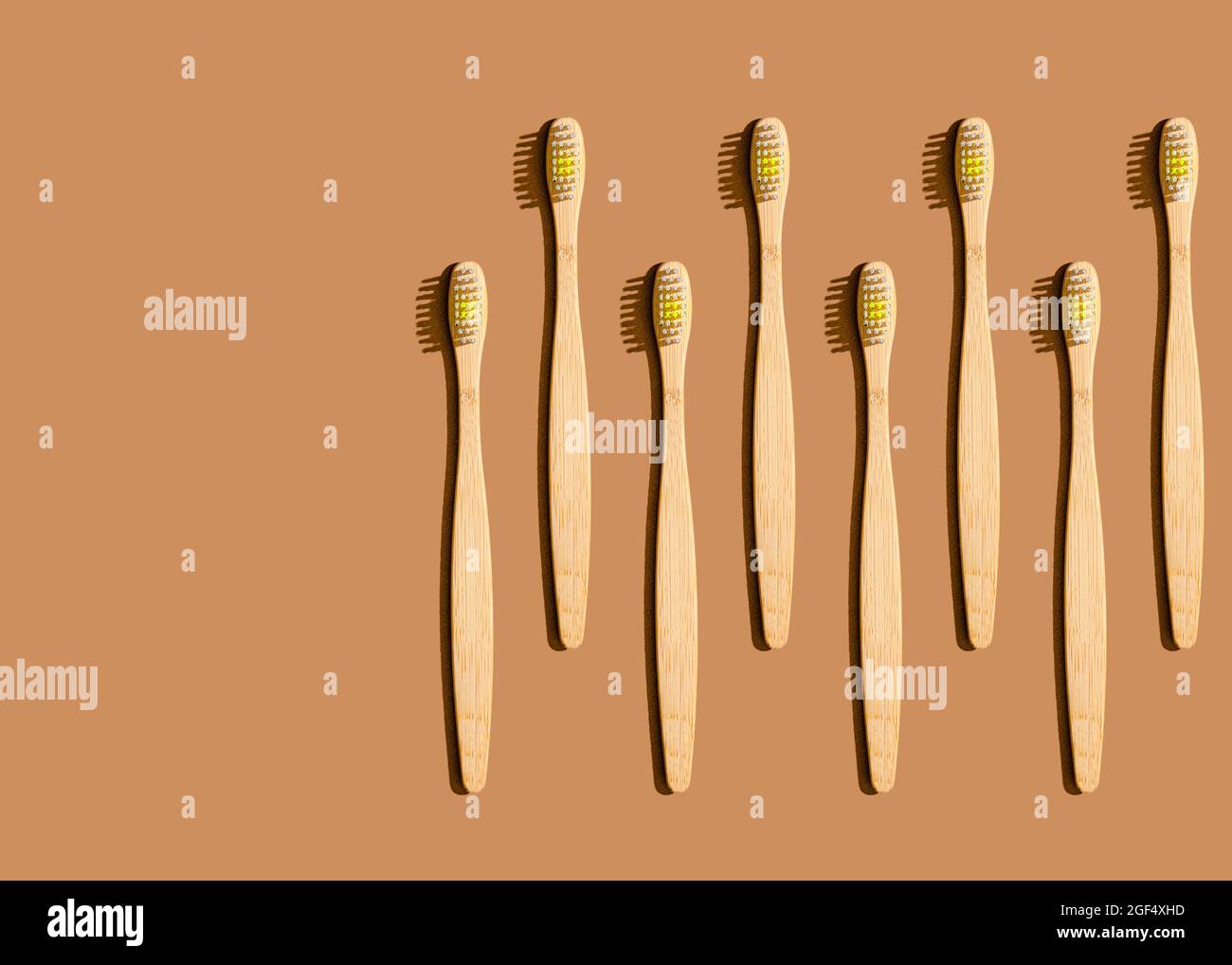 Pattern of wooden toothbrushes flat laid against brown background Stock Photo