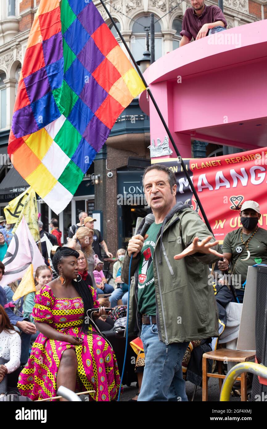 London, England, UK 23rd August 2021 Extinction Rebellions Impossible Rebellion begins in Trafalgar Square, marching towards the Strand, blocking the Long Acre and St Martins Lane intersection with a giant pink table and chairs, speakers including comedian Mark Thomas addressed the crowd assembled Credit: Denise Laura Baker/Alamy Live News Stock Photo