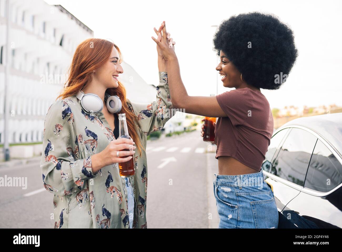 Smiling female friends giving high-five on road Stock Photo