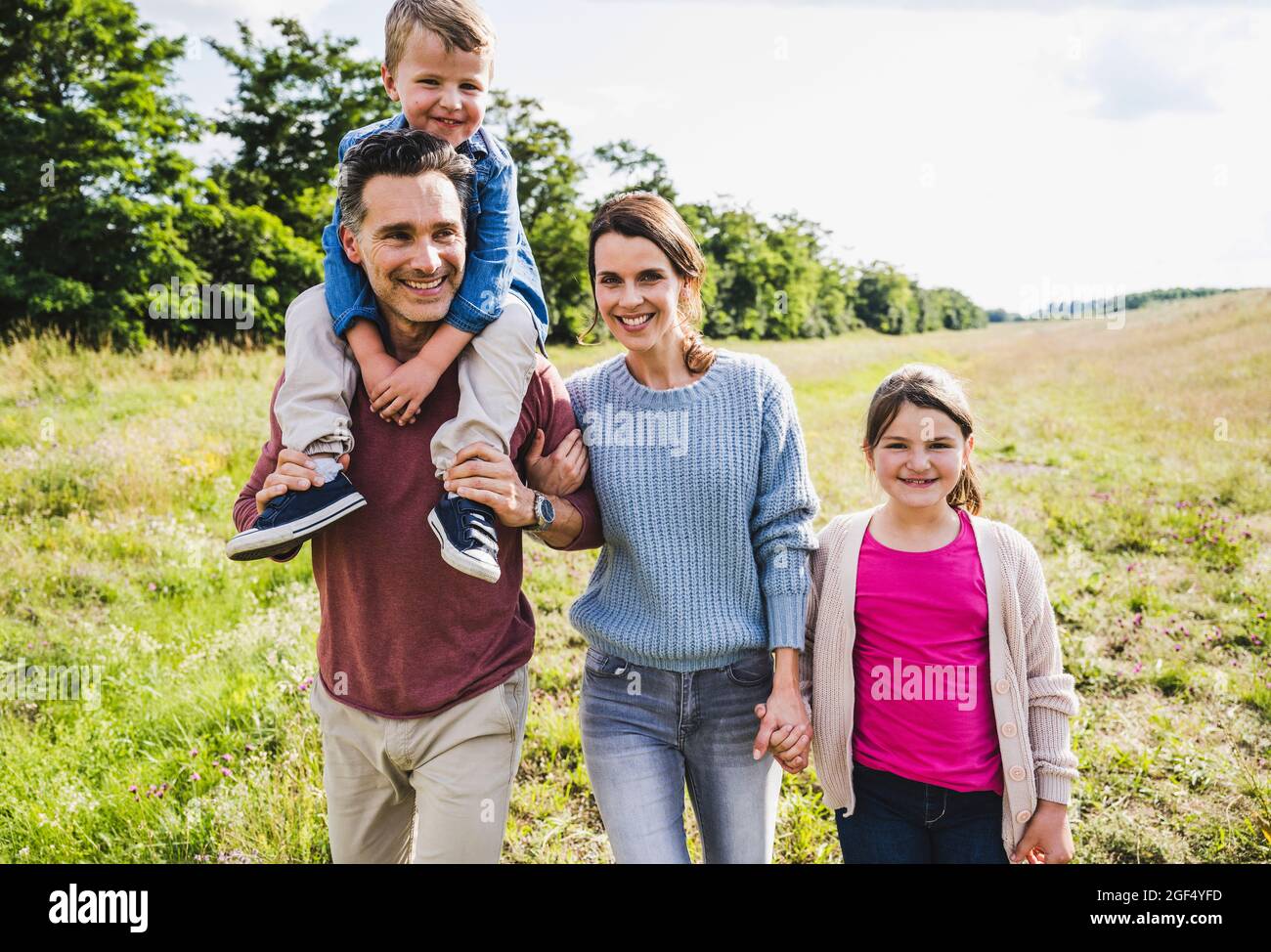 Smiling family walking at meadow on sunny day Stock Photo