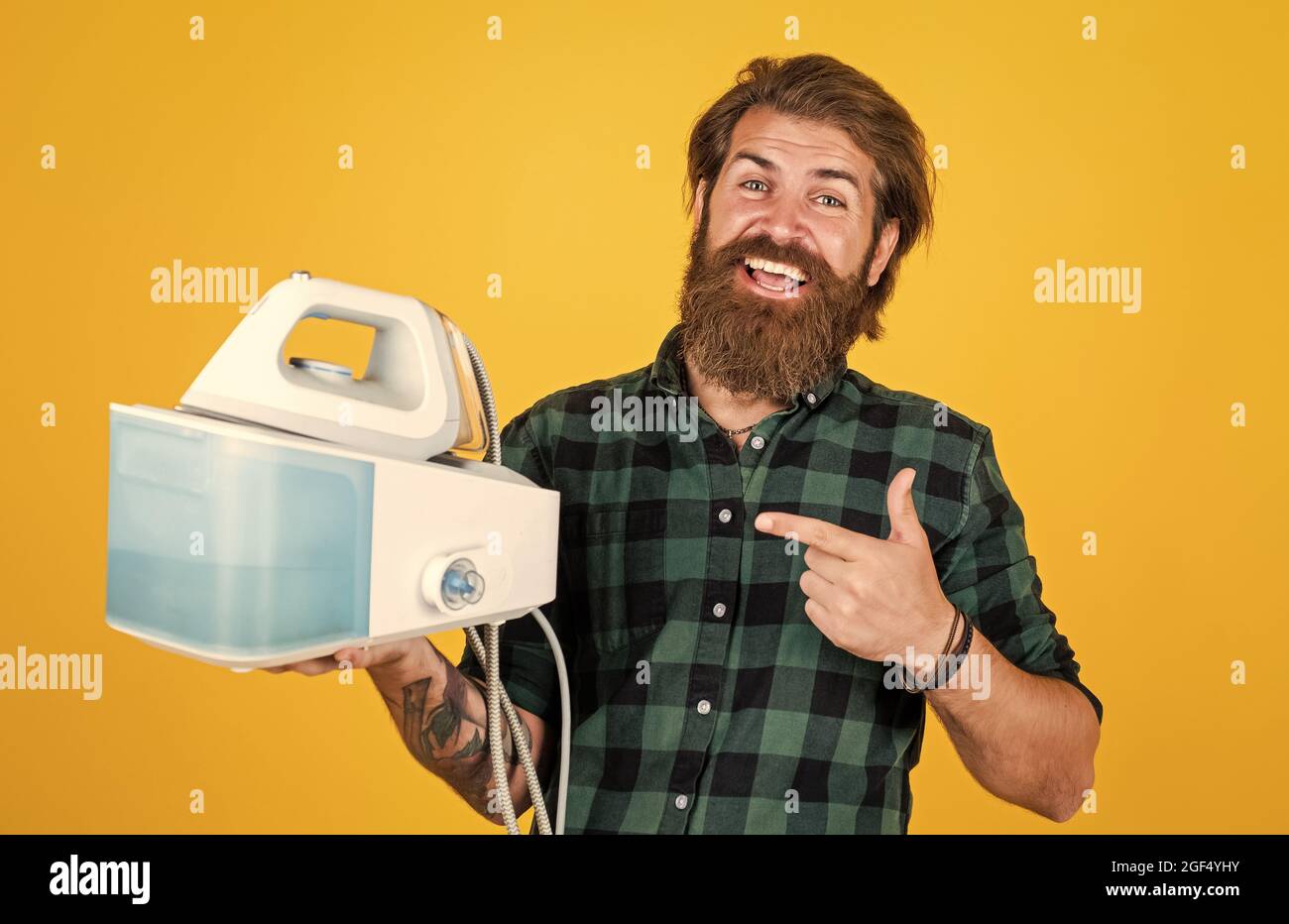 You cant live without it. Man at home ironing clothes. happy house husband. Housekeeping. mature young man husband doing clothing ironing at home. hot Stock Photo