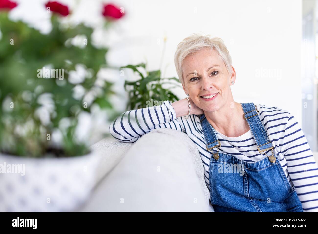 Mature woman sitting on sofa at home Stock Photo - Alamy