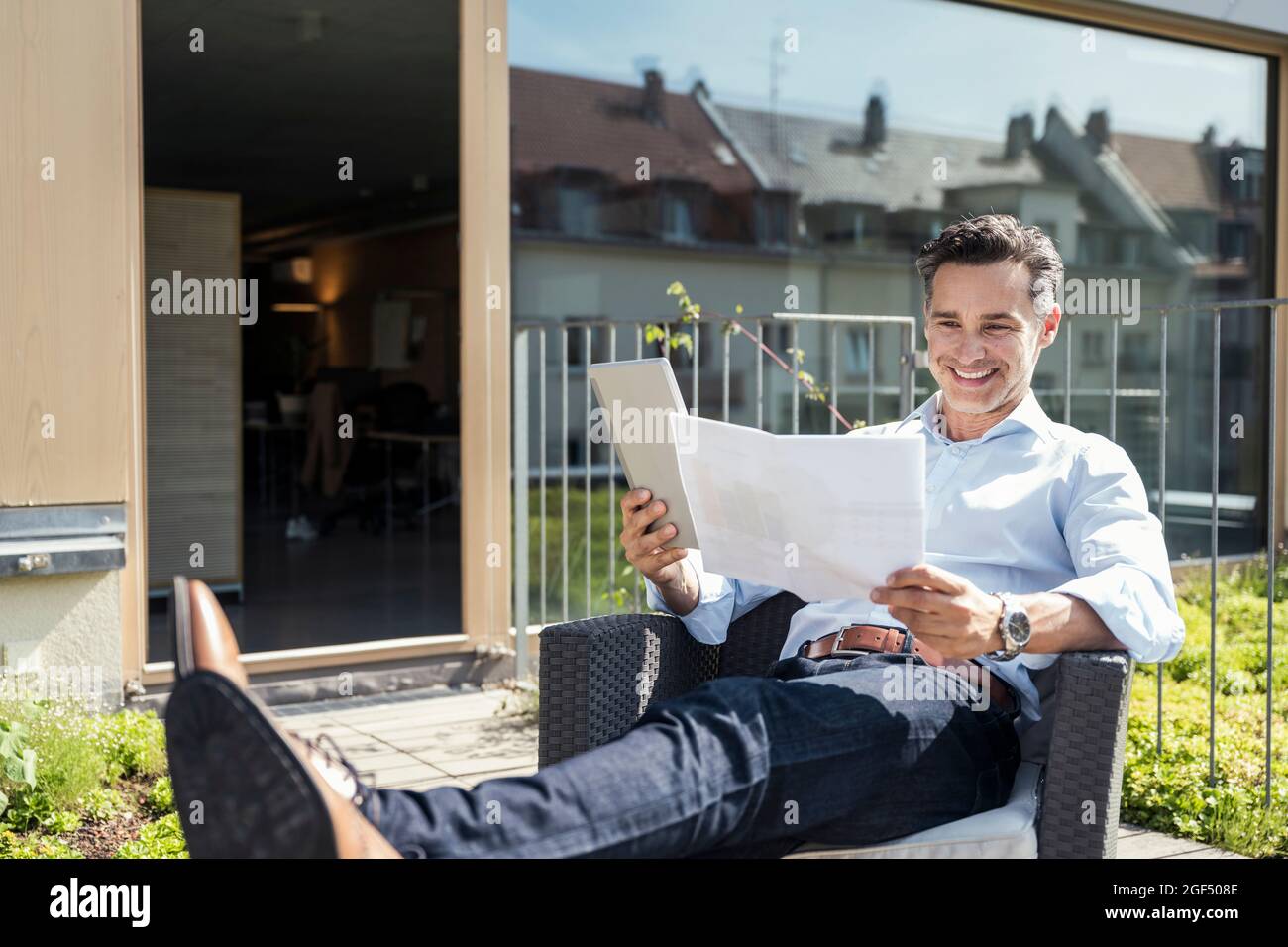 Smiling businessman checking documents while sitting on armchair Stock Photo