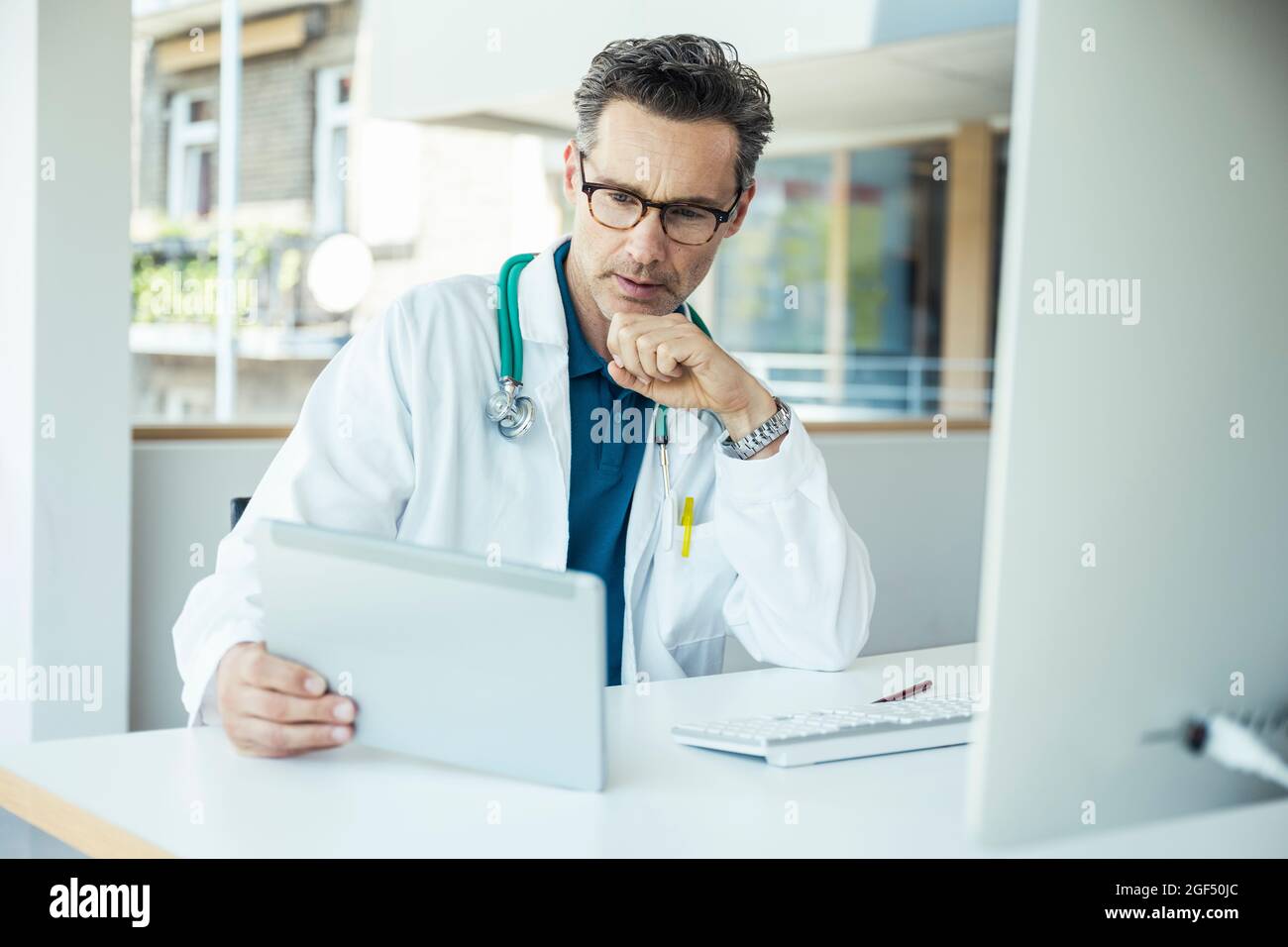 Male doctor using digital tablet while sitting at office Stock Photo