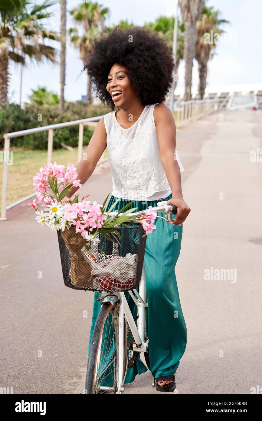 Cheerful young woman riding bicycle on road Stock Photo