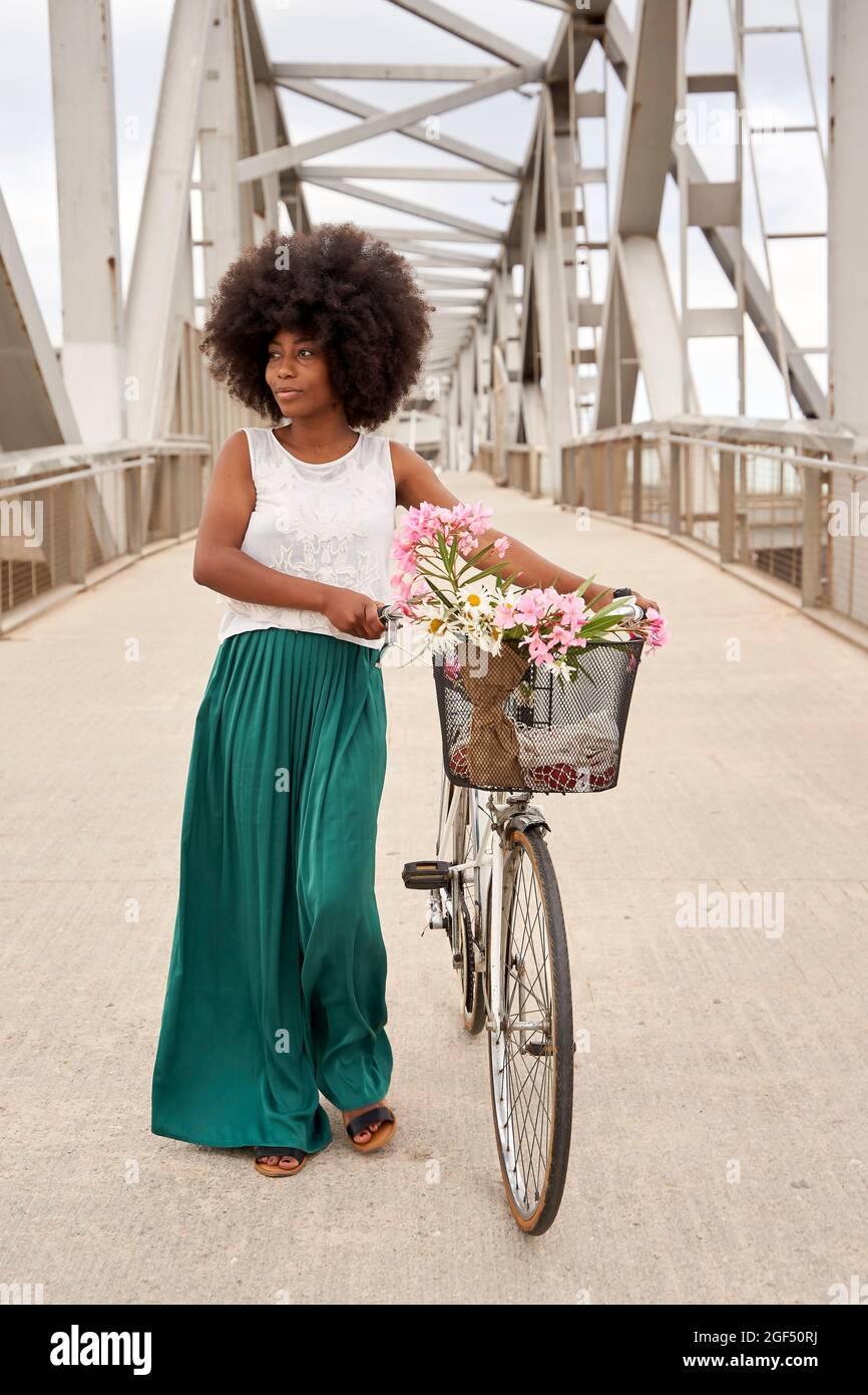 Woman with bicycle walking on bridge Stock Photo