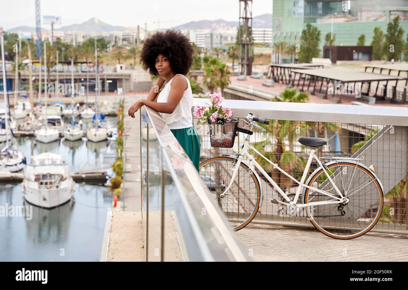 Woman standing with bicycle by railing at harbor Stock Photo