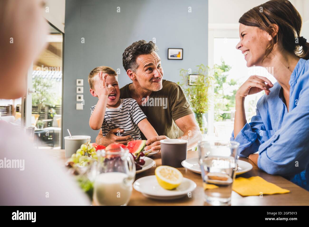 Playful father and son teasing woman while having breakfast at home Stock Photo