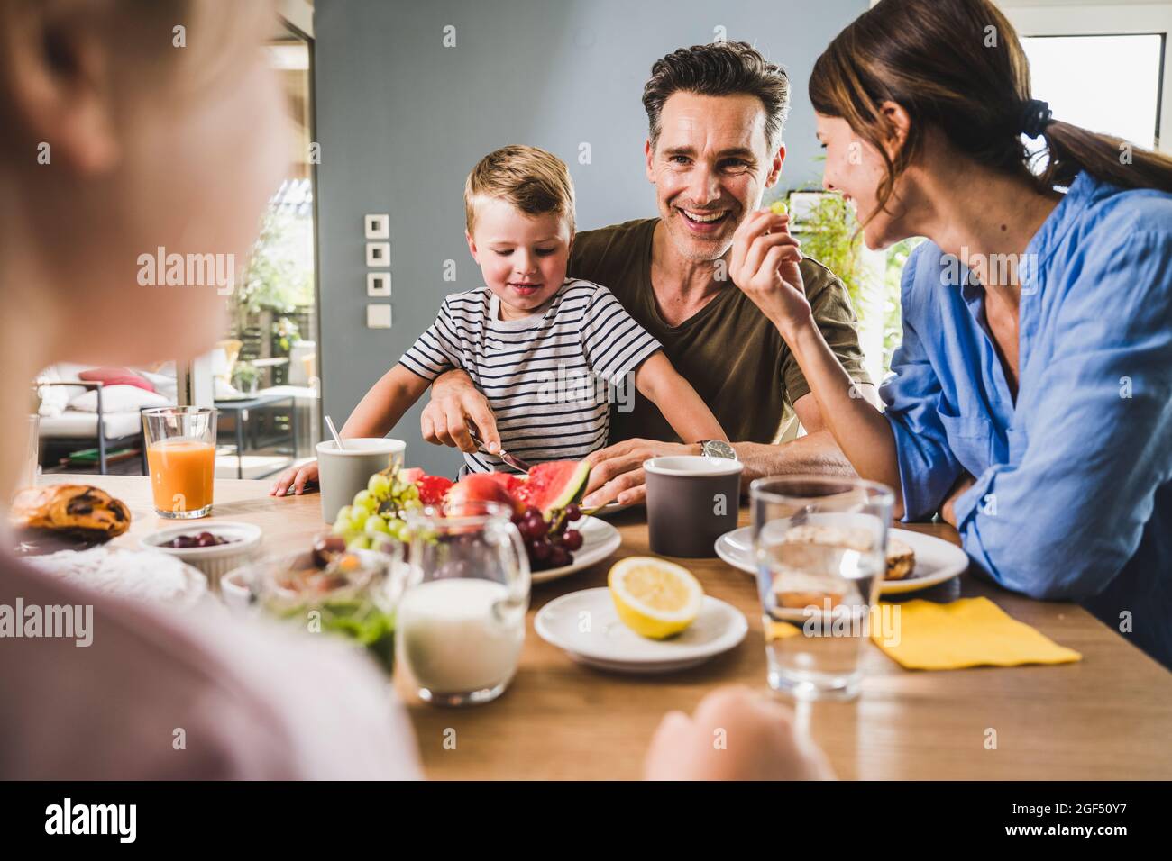 Happy family eating fruits during breakfast at home Stock Photo Alamy
