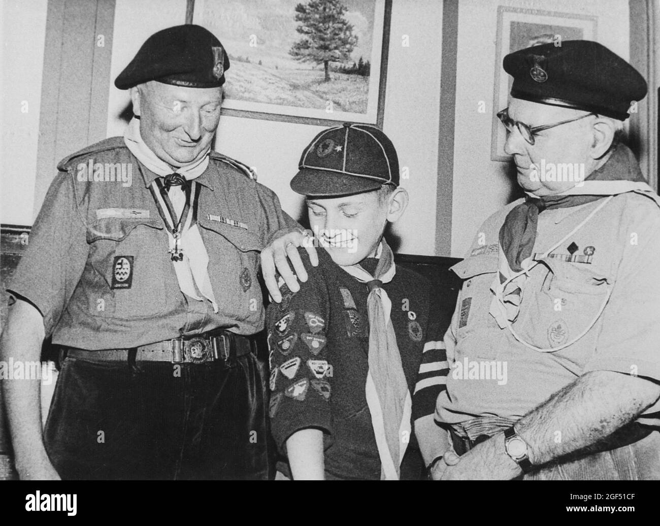 Two elderly London Scoutmasters presenting a ‘Senior Sixer’ Wolf Cub with this thirteenth proficiency badge. 1950s. Stock Photo