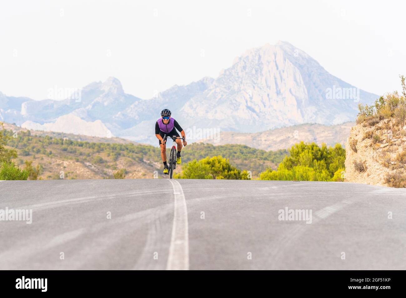 Male sportsperson riding bicycle on mountain road Stock Photo