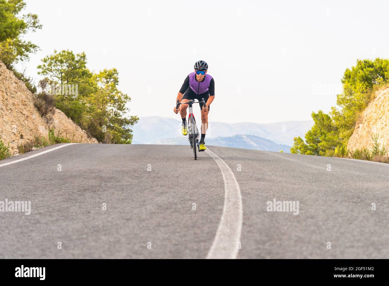 Mature male cyclist riding bicycle on road Stock Photo