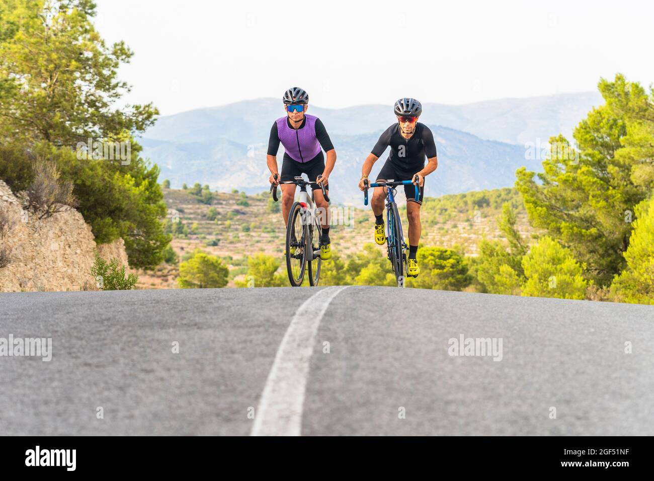 Mature male athletes cycling on road Stock Photo