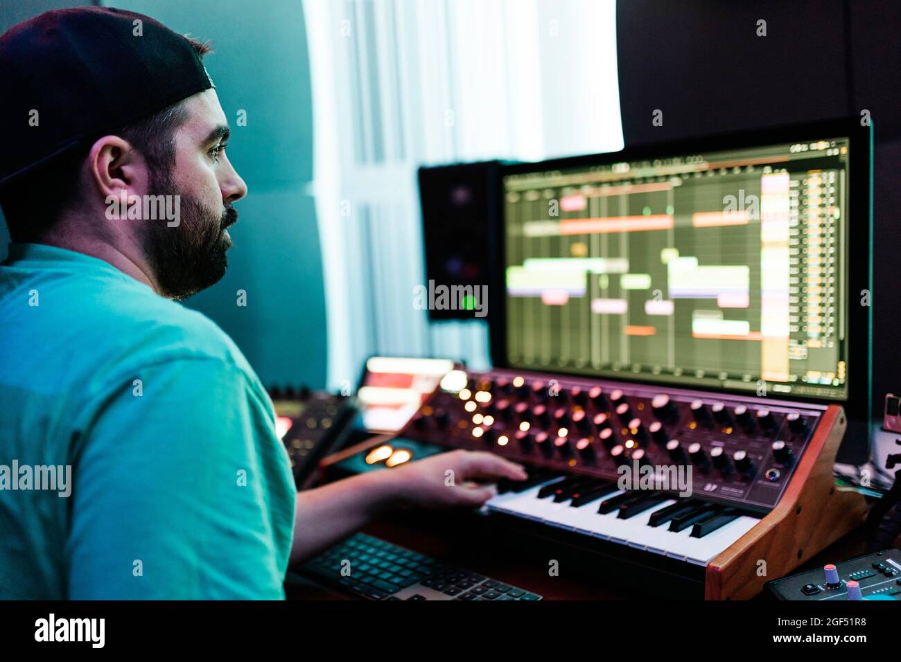 Mid adult male artist playing synthesizer while mixing sound in studio Stock Photo