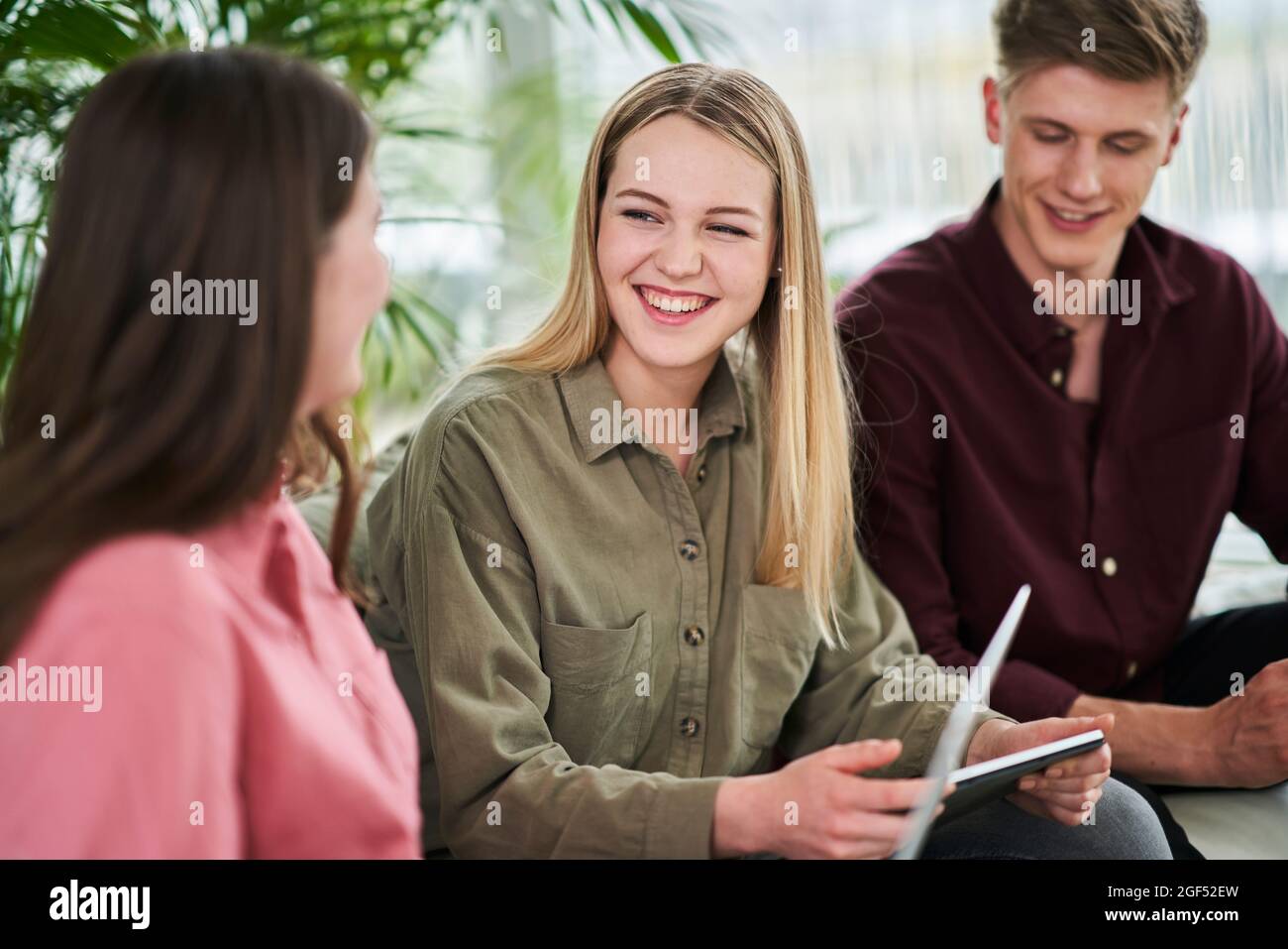 Happy blond female intern discussing with businesswoman while sitting in office Stock Photo