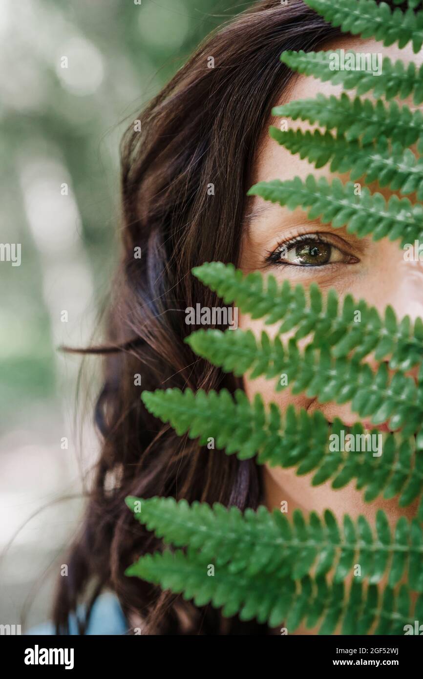 Mid adult woman behind green fern leaf Stock Photo