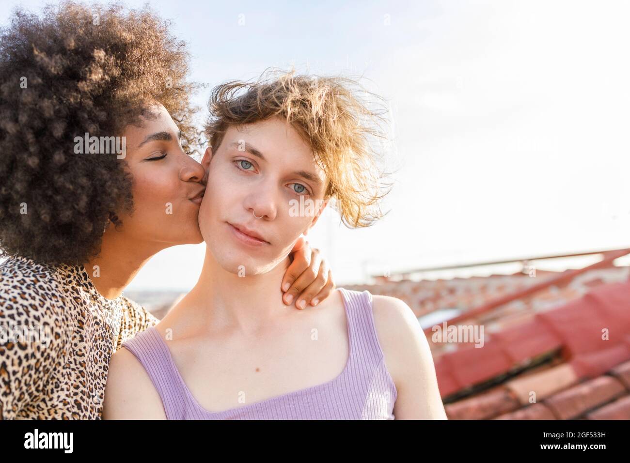 Afro woman kissing male friend on building terrace Stock Photo
