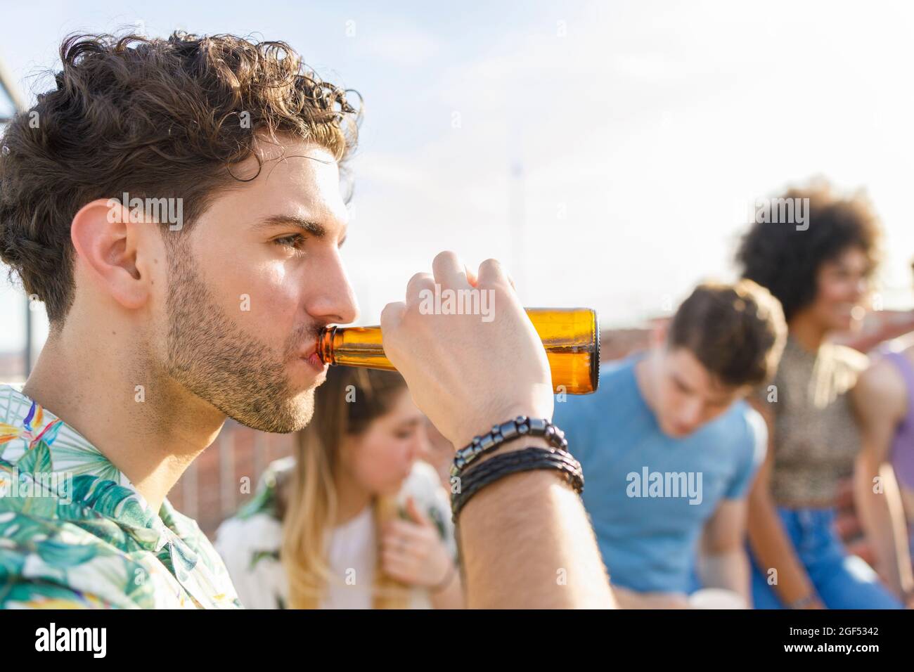 Young man drinking beer during party Stock Photo