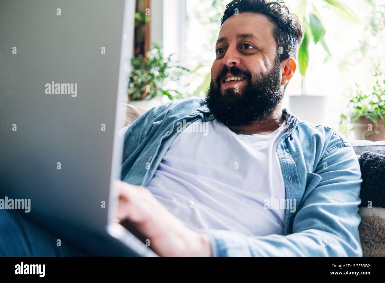 Smiling bearded man using laptop while working at home Stock Photo