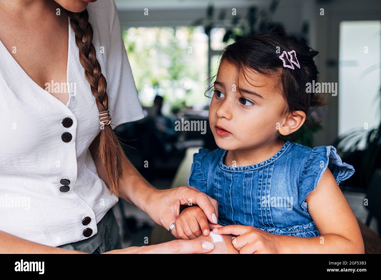 Woman putting adhesive bandage on girl's knee at home Stock Photo