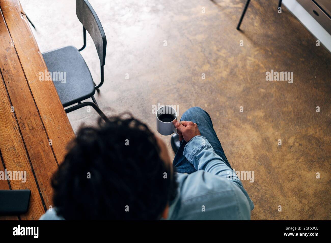 Man holding coffee cup while sitting at table Stock Photo