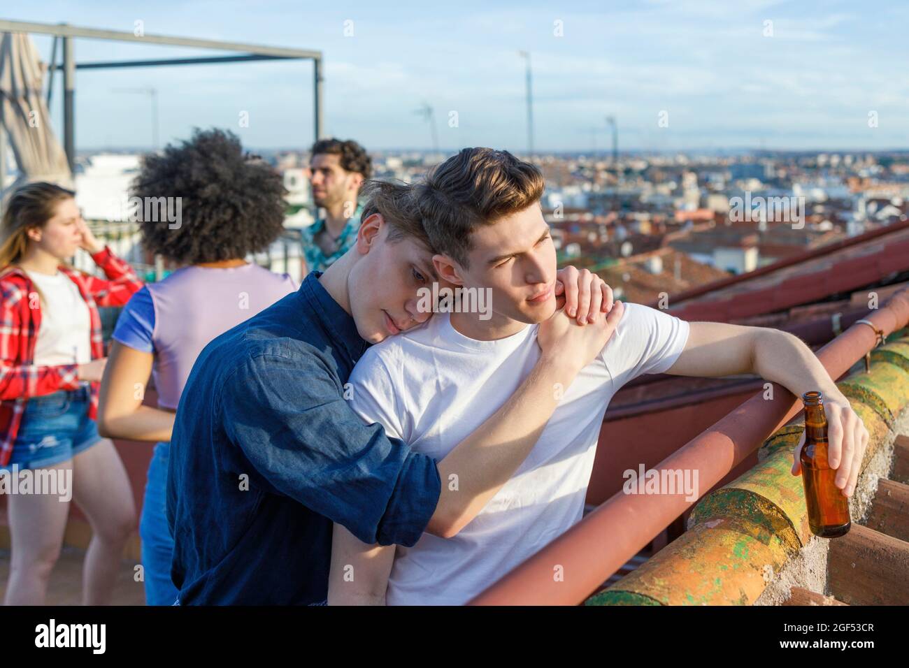 Young man embracing male friend on terrace during party Stock Photo