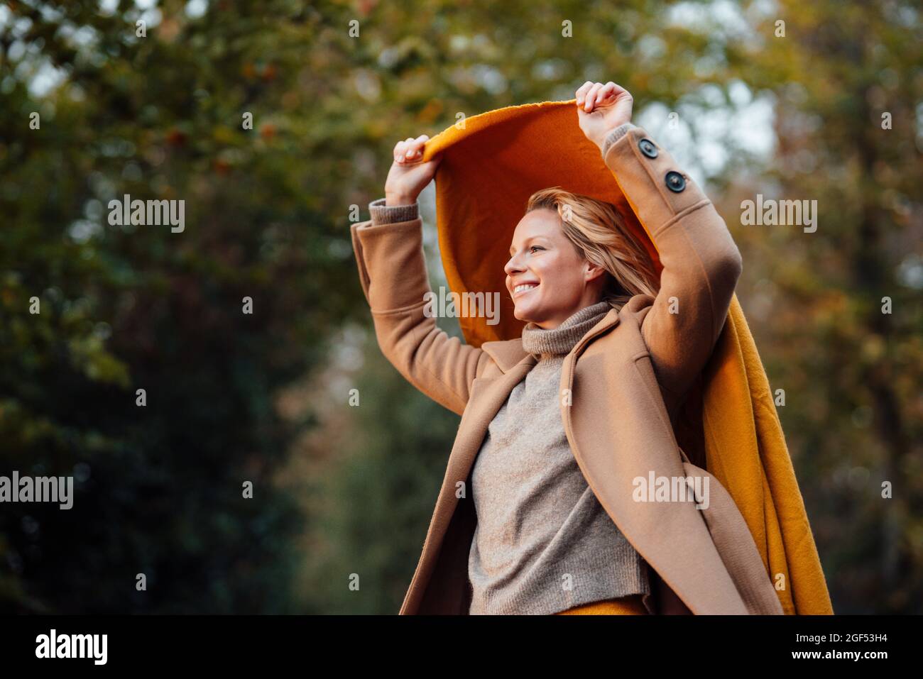 Smiling beautiful woman holding shawl during autumn Stock Photo