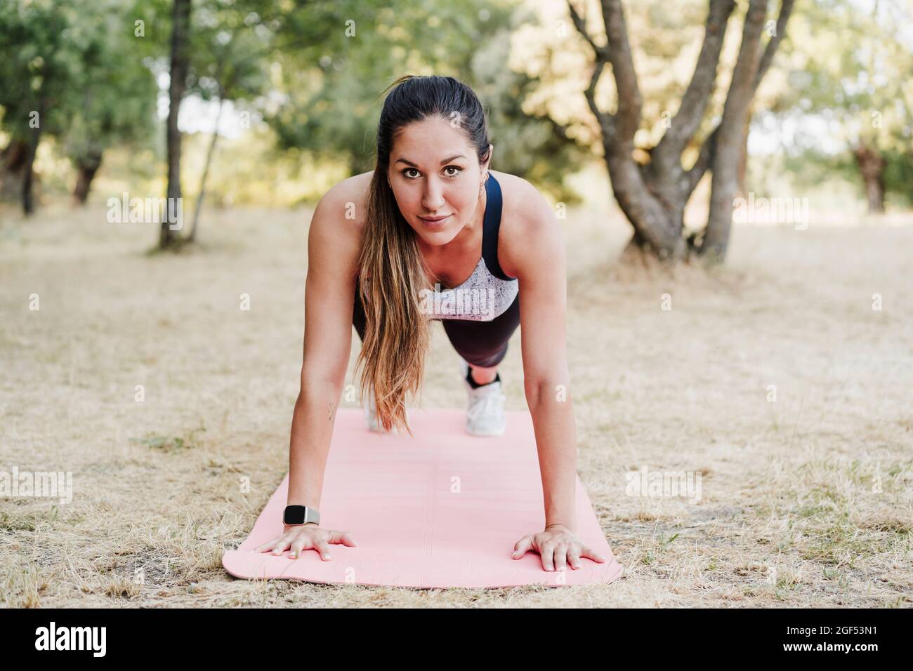 Female athlete doing push-ups in forest Stock Photo