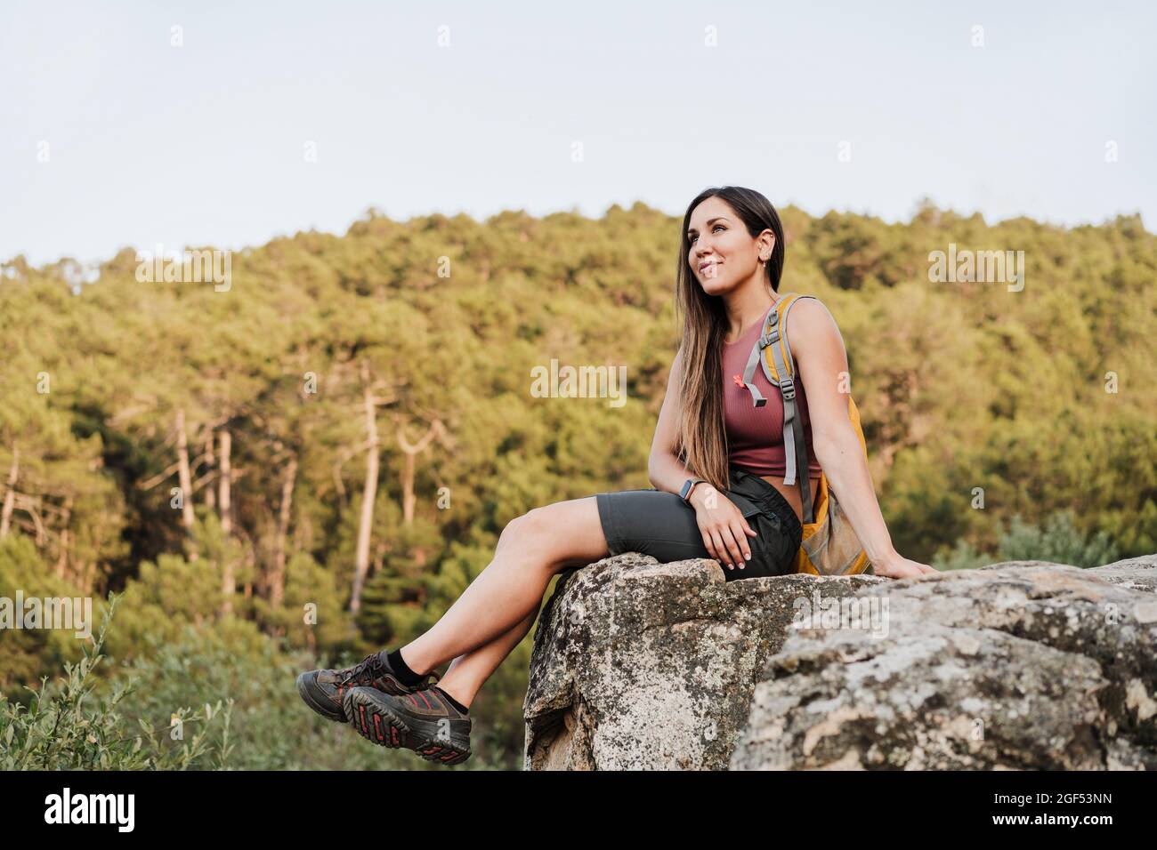 Female hiker with backpack sitting on rock Stock Photo