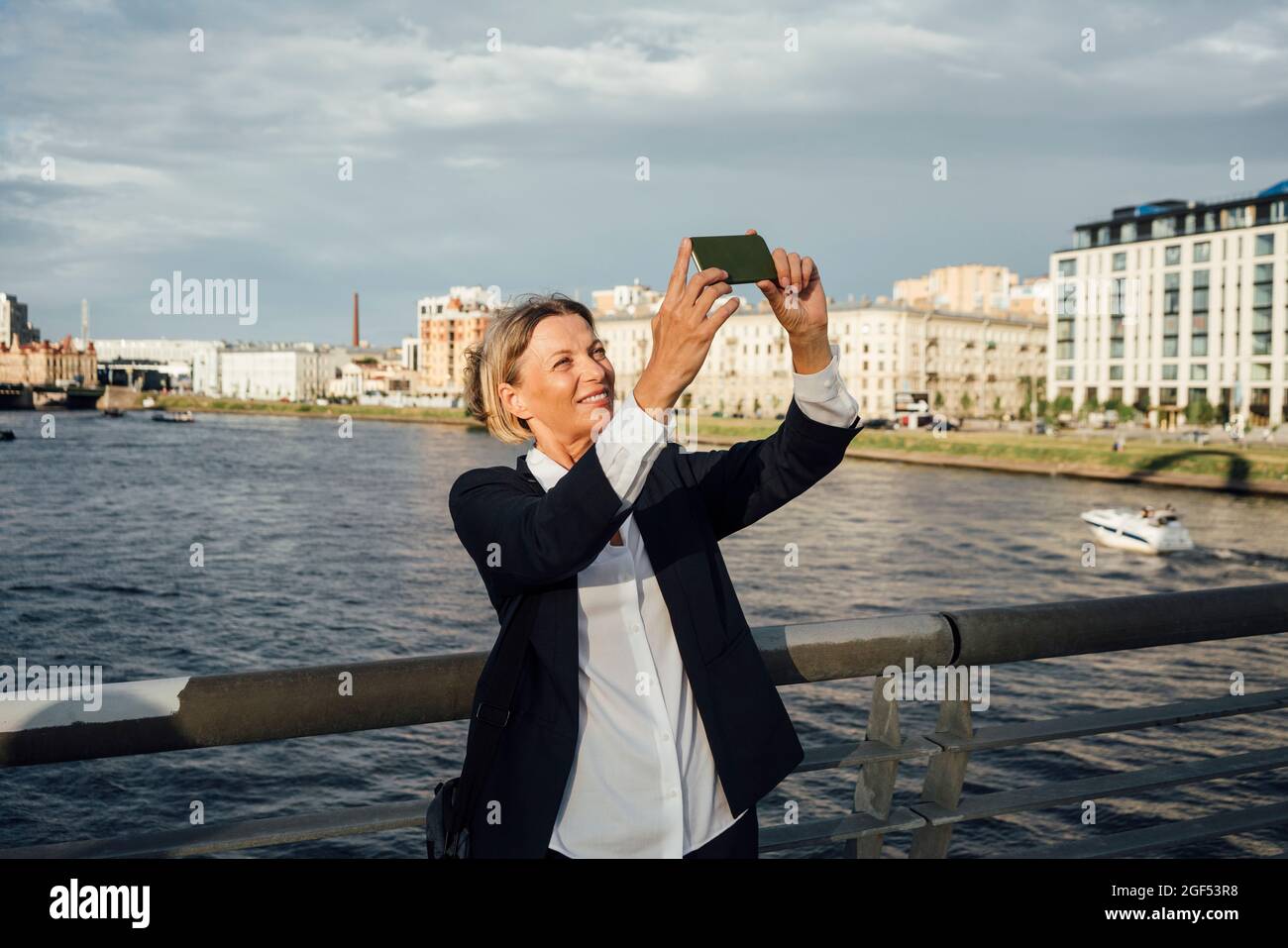 Female professional taking selfie through mobile phone at river Stock ...