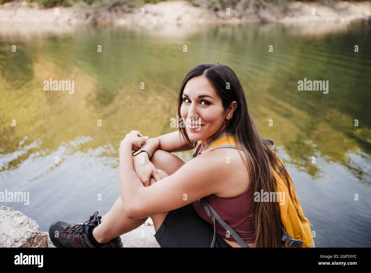 Female hiker sitting on rock by lake during vacation Stock Photo - Alamy