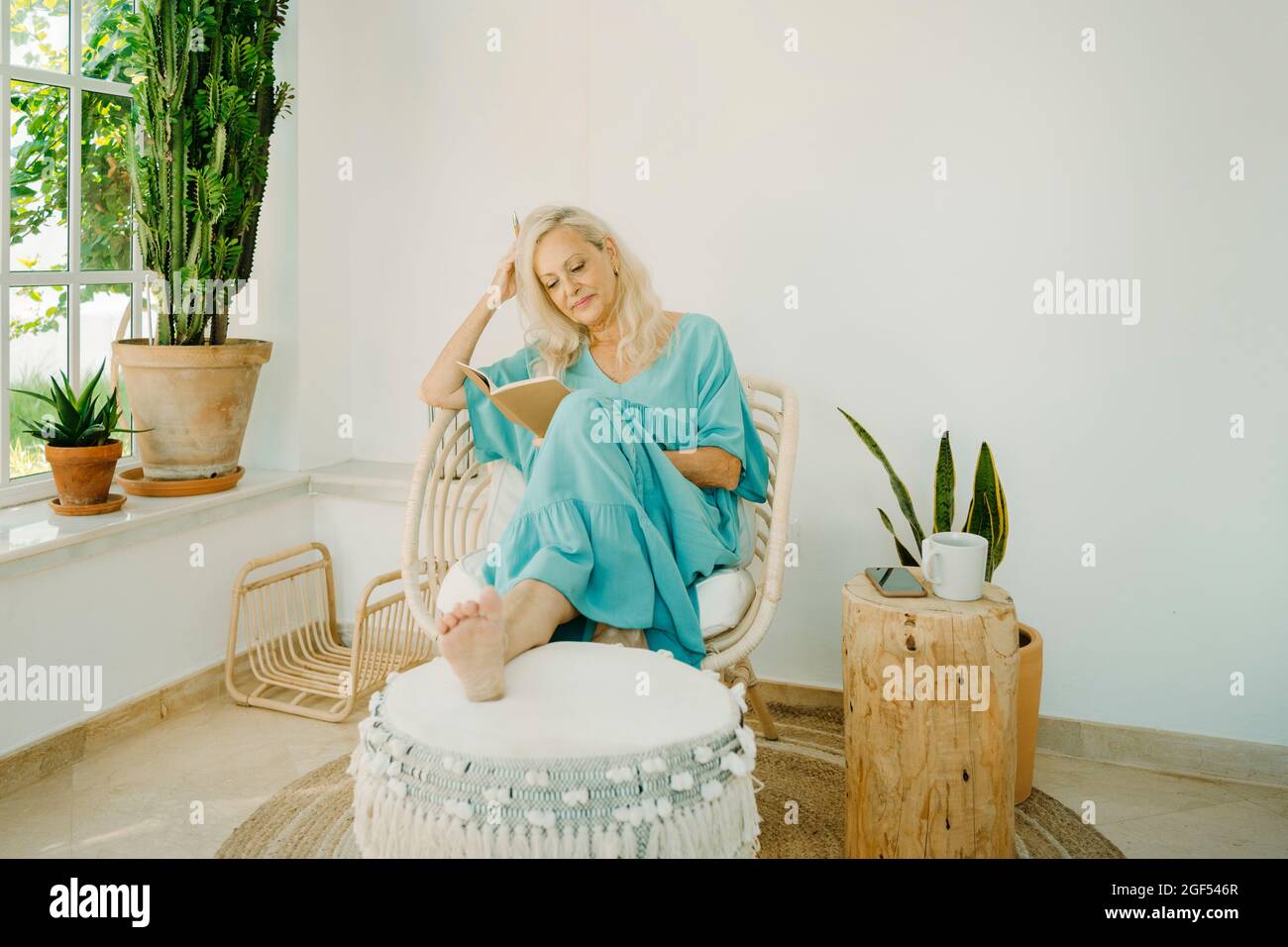 Senior woman reading book while sitting on chair at home Stock Photo ...